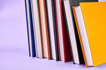 Stack of colorful books on purple background