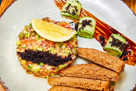 Salmon tartare with red onion, avocado, capers and black bread croutonsの写真素材
