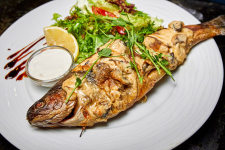 Trout baked in creamy mushroom sauce with lettuce and cherry tomatoesの写真素材
