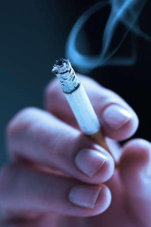 Woman's hand, holding a lit cigaretteの写真素材