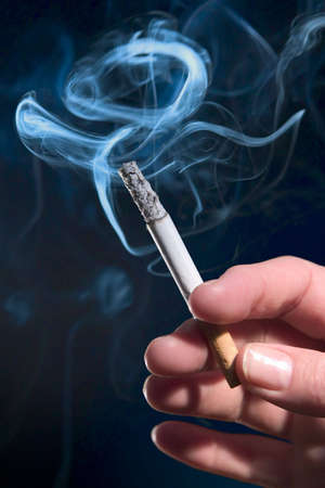 Woman's hand holding lit cigaretteの写真素材