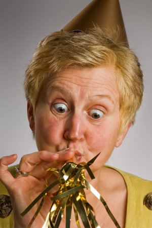 Close-up of mature woman blowing party noise-maker