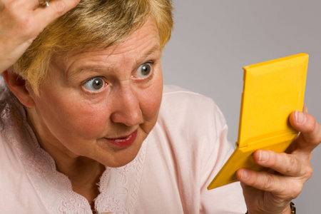 Mature woman checking her appearance using compact mirror