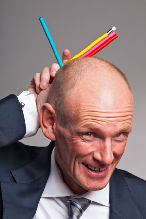 Businessman fooling around with colorful pencilsの写真素材