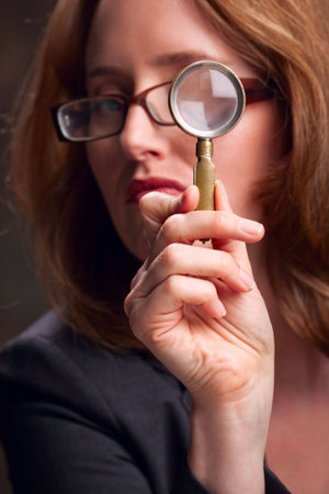 Close-up of woman looking through magnifying glass -- focus on handの写真素材