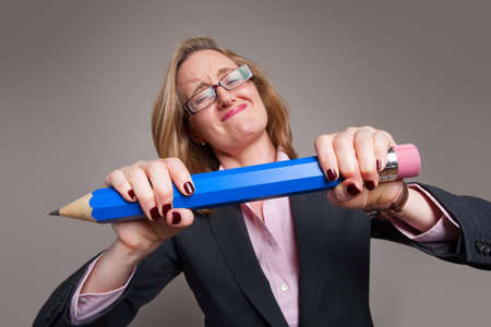 Businesswoman breaking a giant blue pencilの写真素材