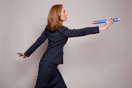 Profile view of woman throwing an oversized pencilの写真素材
