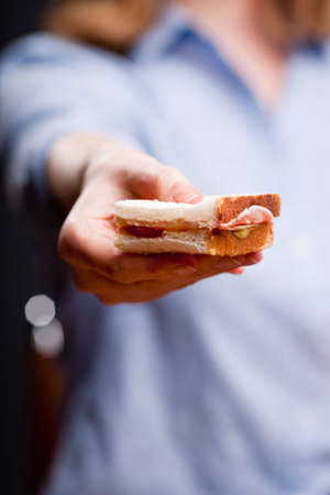 Detail shot of woman's hand offering a sandwich - focus on sandwichの写真素材