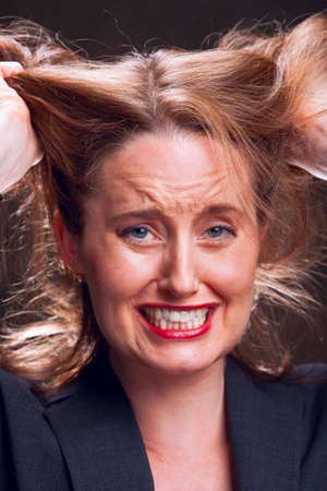 Frustrated businesswoman tearing her hair outの写真素材