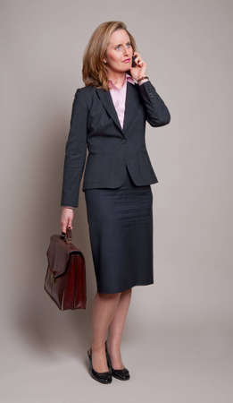 Woman carrying a briefcase and using a mobile phoneの写真素材
