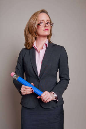 Teacher holding giant blue pencil on grey backgroundの写真素材