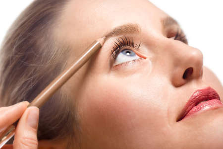 Close-up of woman applying make-up using eyebrow pencilの写真素材