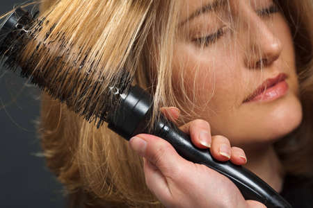 Close-up of hairdresser's hand styling customer's hairの写真素材