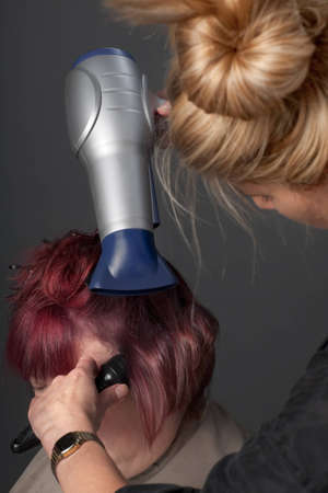 Hairdresser blow drying customer's hairの写真素材