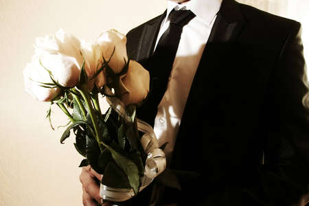 man dressed in a suit wearing a tie and white shirt with white rosesの写真素材