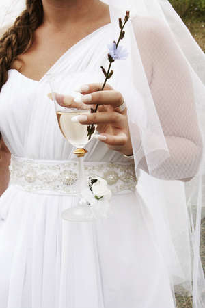 The bride with a glass of champagne and a blue flowerの写真素材