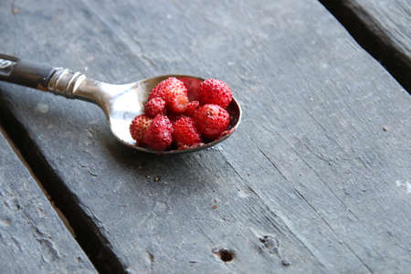 Strawberry in a spoon on a wooden tableの写真素材