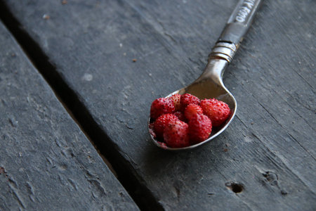 Strawberry in a spoon on a wooden tableの写真素材