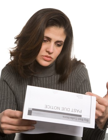 Young woman looks sad with past due notices in front of herの写真素材