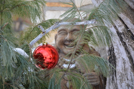 A wooden troll hides behind a Christmas tree decorationの写真素材