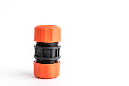 Orange garden water hose nozzle and connectors isolated on white background with soft shadow.