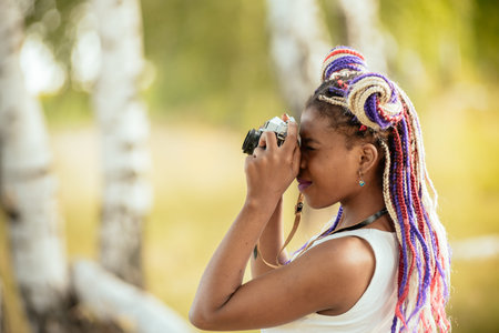 happy young african american female photographer looking to vintage camera
