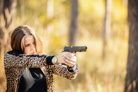 portrait of a beautiful pregnant young girl with a gun in her hands against the backdrop of an...