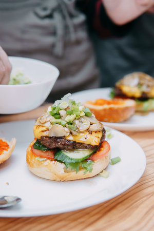 Burgers with beef and vegetables, the cooking process, hands collecting the burger. Delicious...