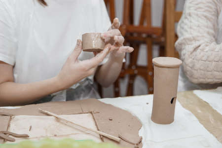 Womens hands knead clay, drawing elements of the product. Production of ceramic products at the master class on ceramics.の写真素材