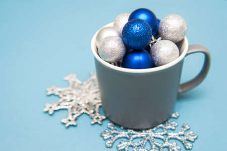 Blue and silver Christmas balls in a Cup on a blue background. Creative concept of Christmas and New year.の写真素材