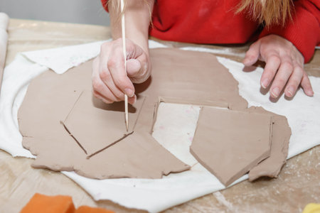 Womens hands knead clay, drawing elements of the product.