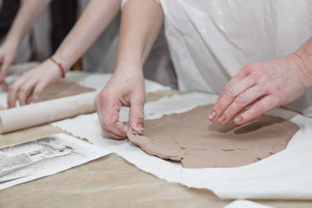 Womens hands knead clay, drawing elements of the product. Production of ceramic products at the master class on ceramics.の写真素材