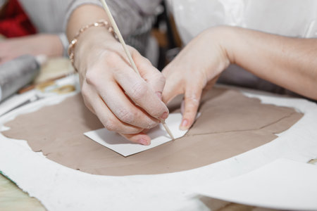 Womens hands knead clay, drawing elements of the product. Production of ceramic products at the...