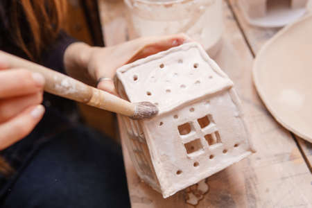 A master ceramist holds a clay product in his hands. Making a ceramic candle holder from clay. The process of coating the candlestick with glaze.の写真素材