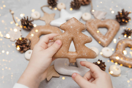 Childrens hands hold a gingerbread in the shape of a Christmas tree. The concept of Christmas...