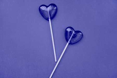 Purple lollipops in the form of hearts on a purple background. The concept of Valentines Day. Demonstrating the colors of 2022 - Very Peri.の写真素材