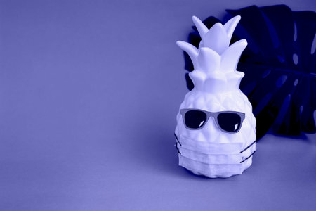 Pineapple in a medical mask and sunglasses on very peri background. Summer concept. Vision for the summer of 2022 during the coronavirus pandemic. Demonstrating the colors of 2022 - Very Peri.の写真素材
