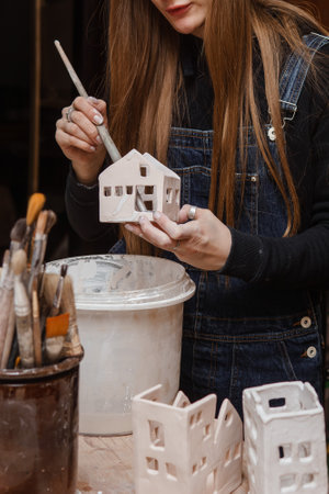 A master ceramist holds a clay product in his hands. Making a ceramic candle holder from clay. The process of coating the candlestick with glaze.の写真素材