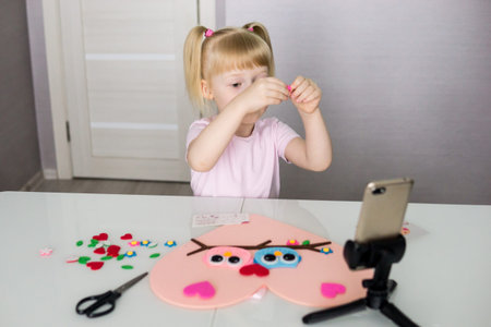 A blogger girl makes a felt craft for Valentines Day in the shape of a heart. The concept of...