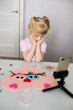 A blogger girl makes a felt craft for Valentines Day in the shape of a heart. The concept of...