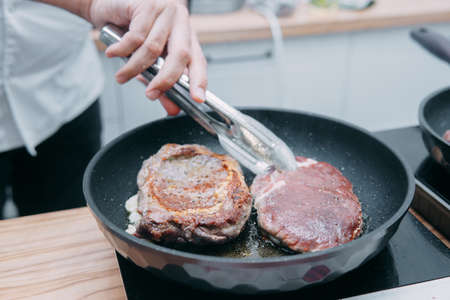 Cooking beef ribeye steak in a frying pan in the cooking class. Steak with spices. Cooking process, close-up.の写真素材