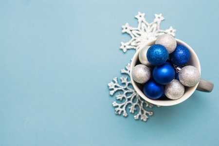Blue and silver Christmas balls in a Cup on a blue background. Creative concept of Christmas and New year.の写真素材
