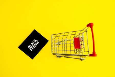 Shopping cart, and a black square that says black Friday on a yellow background. The topic of sales.の写真素材