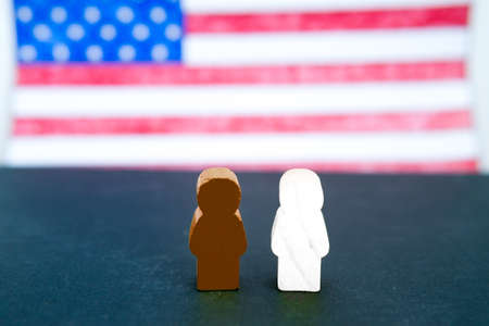 Black and white figures of people on the background of the American flag. Motivational poster against racism and discrimination. Space for text, selective focus.の写真素材