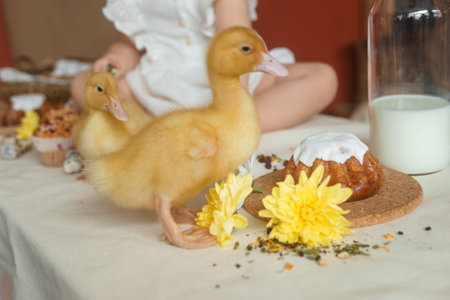 Cute fluffy ducklings on the Easter table with quail eggs and Easter cupcakes, next to a little...