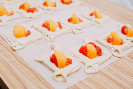 Preparing a dessert at a cooking master class. Baskets with peaches and strawberries, home cooking. Close-up, selective focus. Pastries, pies with peaches from puff pastry.の写真素材