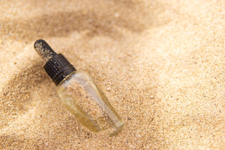 Cosmetic serum in a glass bottle with a pipette in the sandの写真素材