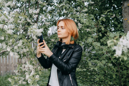 A red-haired teenage girl with headphones around her neck takes a selfie against the background of a...