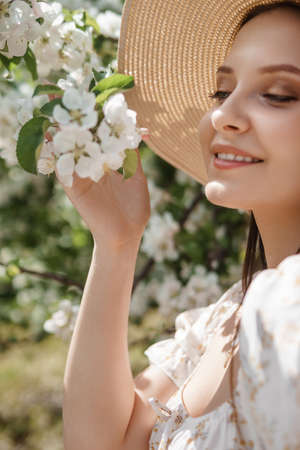 An attractive long-haired woman walks in the spring in the park of blooming apple trees.の写真素材