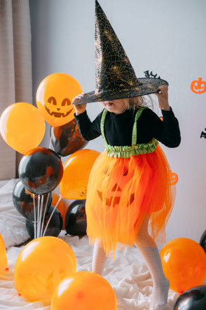 Childrens Halloween - a girl in a witch hat and a carnival costume with airy orange and black...